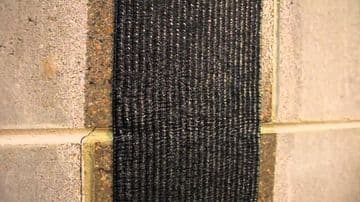 Carbon fiber reinforcement applied to a concrete wall, showcasing innovative foundation repair technology by StablWall for structural stability.