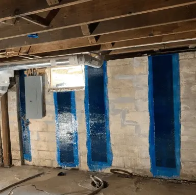 Basement wall with blue carbon-fiber reinforcement strips applied for structural stabilization, showcasing StablWall's innovative foundation repair solutions.
