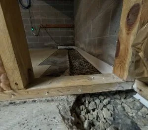 Interior basement drainage system installation with gravel trench and wall channel