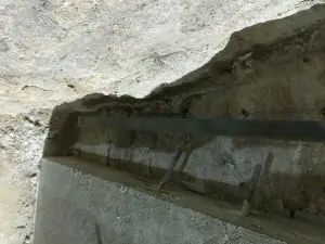 Technician inspecting sinking foundation repairs in Roanoke, VA showing exposed concrete footing and steel reinforcement during structural repair.