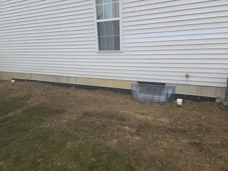 Completed exterior basement waterproofing project in Toledo, OH showing restored grading, foundation protection membrane, and waterproofed foundation wall.