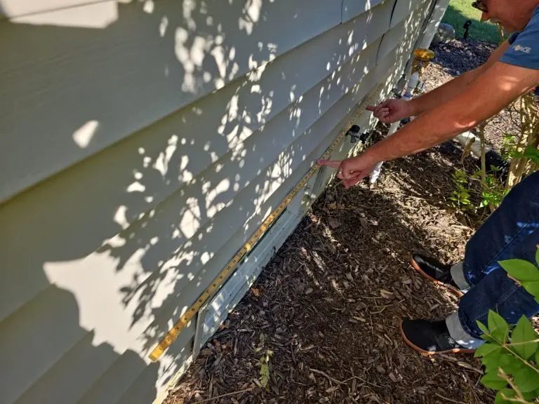 Toledo basement waterproofing inspection measuring the exterior foundation of a home for signs of water intrusion