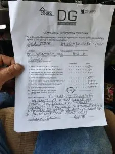Completion certificate for basement waterproofing by Toledo Basement Repair, held by a person, featuring handwritten notes and ratings, dated August 2, 2018, Bowling Green, Ohio.