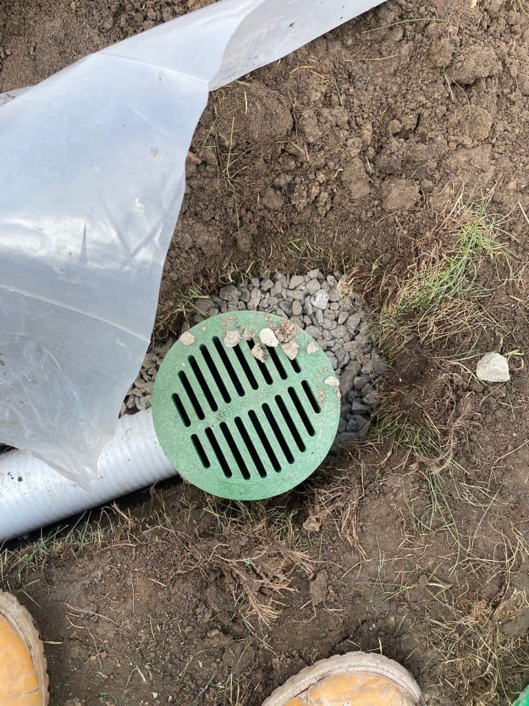 Exterior drainage basin outlet installed near foundation to discharge water from basement sump pump system in Toledo, OH.