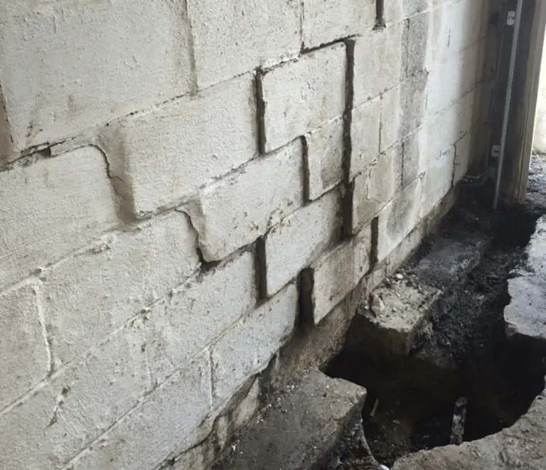 Bowing basement walls in Toledo with displaced concrete blocks and excavation near the foundation