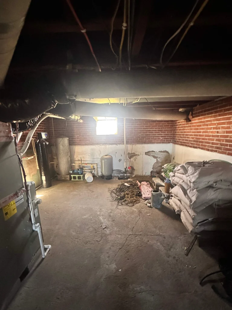 Damp unfinished basement in Napoleon OH farmhouse before crawlspace encapsulation and sump pump installation