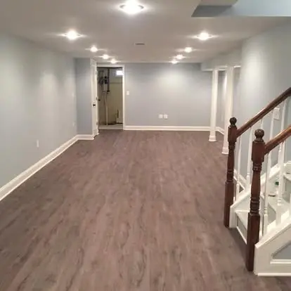 Newly installed flooring in a finished New Jersey basement with recessed lighting and staircase