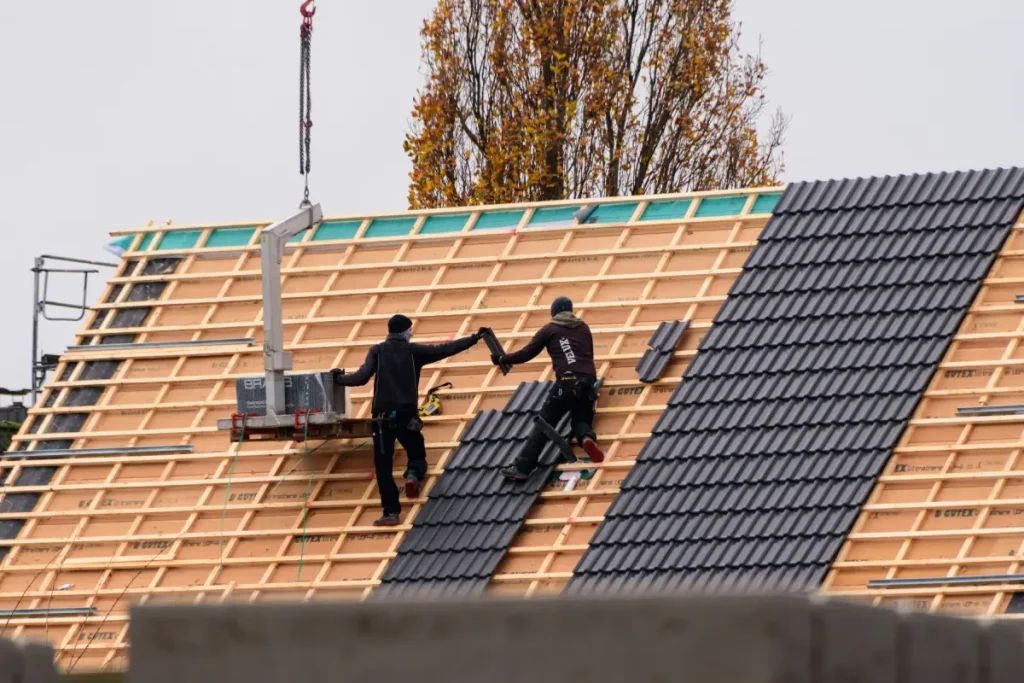 Roofers completing the roofing installation process on a New Jersey home with dark roof tiles