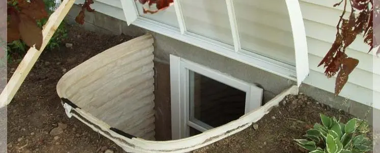 Basement egress window installation services showing a newly installed egress window well with protective cover for improved safety and waterproofing.