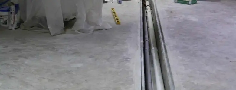 Interior basement drainage system installation with perimeter drain channel and waterproofing components