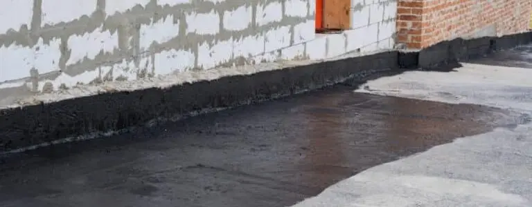 Fresh waterproofing membrane applied along a home's foundation by basement waterproofing contractors near me to protect against moisture intrusion.