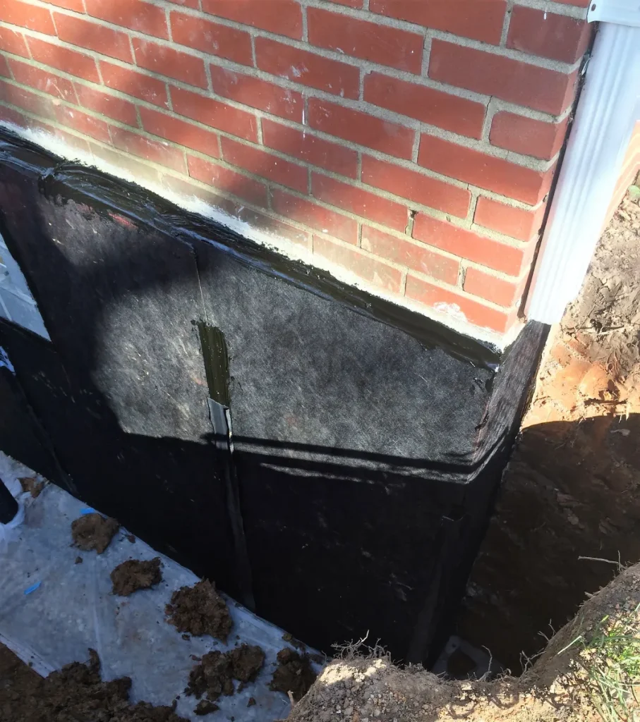 Exterior foundation wall protected with a waterproofing membrane before backfilling.
