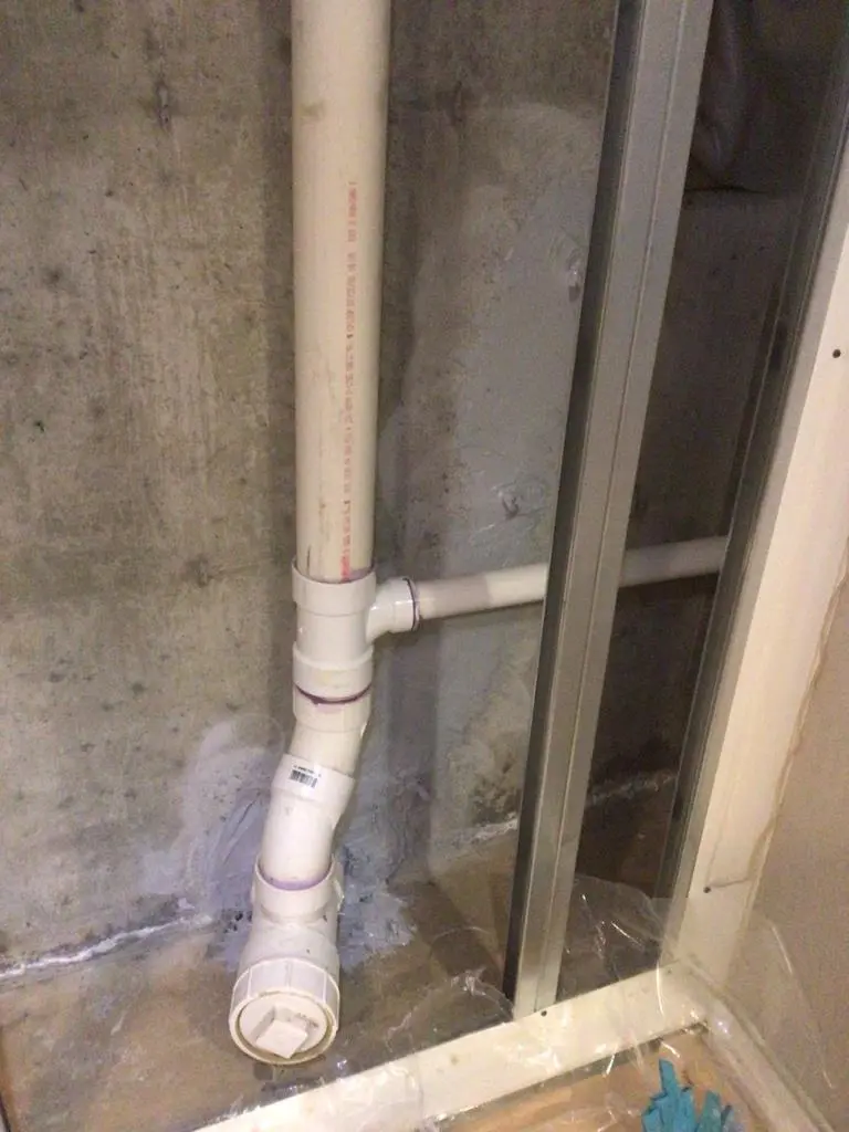 Foundation crack repair near septic pipe penetration in a basement wall in Killingworth, CT with waterproofing and reinforcement work in progress.