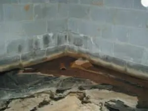 Damp basement floor example against a brick wall
