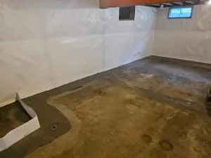 Interior perimeter drainage system installed along a basement wall before concrete restoration to prevent flooding and relieve hydrostatic pressure.
