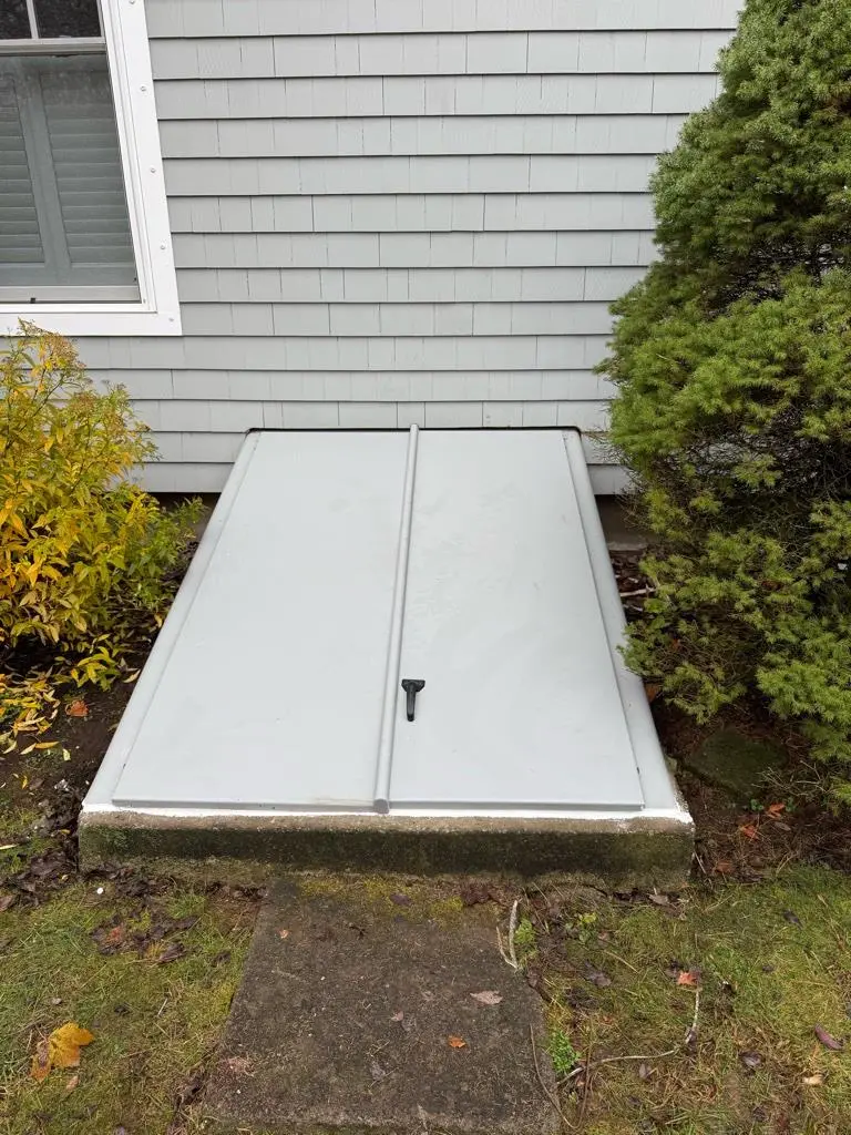 New gray Bilco basement hatchway door installed in Waterford, CT, providing waterproof protection and enhanced security for the basement entrance.