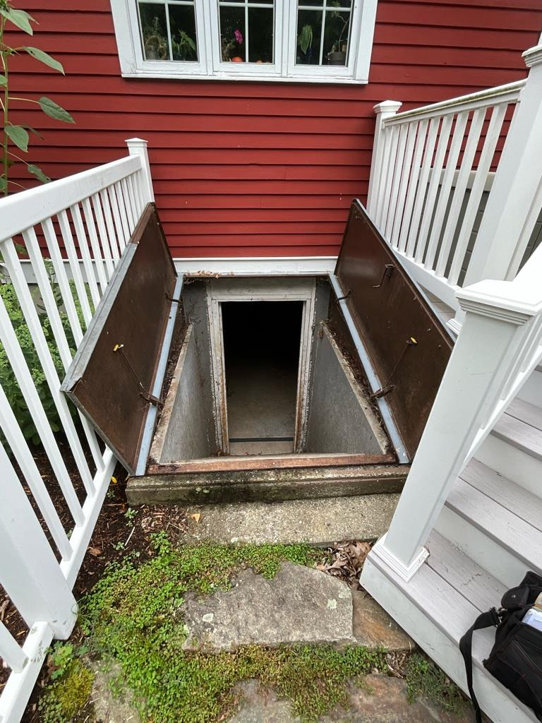 Old rusty Bilco basement hatchway door open showing stairs in Killingworth CT home