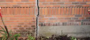 Vertical foundation crack in a brick wall showing structural settlement and foundation damage