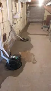 Interior basement waterproofing system with sump pump, drainage channel, and sealed concrete floor to prevent water intrusion