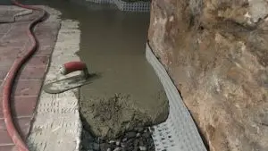 Wet concrete being applied during work to prevent basement water damage along a foundation wall