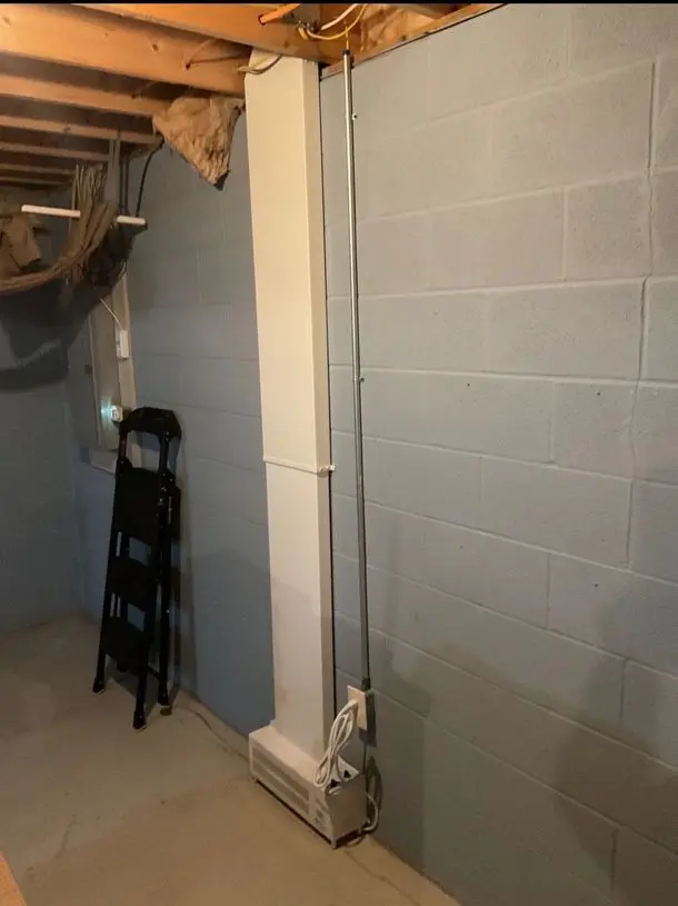 Basement ventilation system installed in a home, showcasing a white ventilation unit against a gray wall, emphasizing air quality improvement for healthier living.