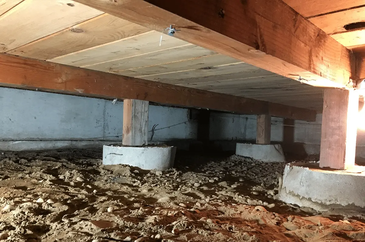 Crawlspace interior showing wooden beams, concrete supports, and sandy ground, highlighting moisture control for improved air quality and prevention of structural damage.
