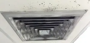 Ceiling ventilation duct with visible mold and dust buildup, highlighting issues related to indoor air quality and the importance of proper ventilation systems.