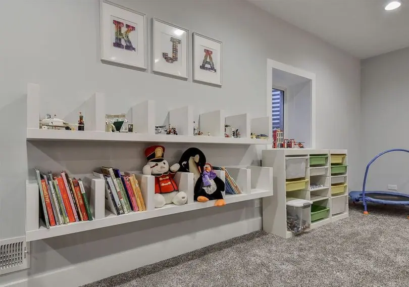 Children's playroom with organized bookshelves, plush toys, and storage bins, emphasizing a clean and inviting space for indoor activities.