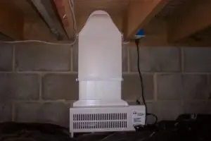 Basement ventilation system installed to improve air quality and prevent mold growth, featuring a white unit against a concrete wall.