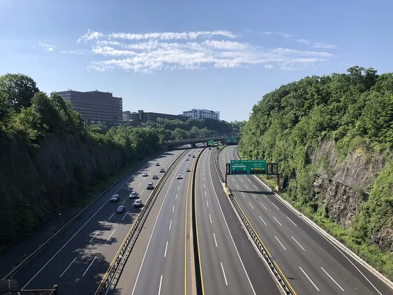 Highway scene in Leonia, NJ, showing multiple lanes of traffic, green road signs indicating directions, and lush greenery along the roadside, representing accessibility for HealthyWay Waterproofing & Mold Remediation services.