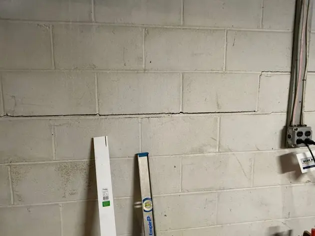 Foundation crack repair in New Jersey basement wall with measuring tool.