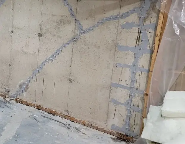 Foundation wall with visible cracks and repair work in progress, highlighting structural concerns relevant to basement waterproofing and foundation repair in New Jersey.