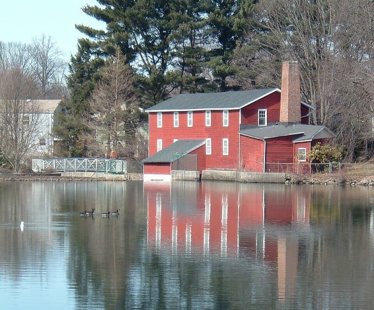 Red house and pond reflecting water in Bergenfield, NJ, protecting homes from water damage.