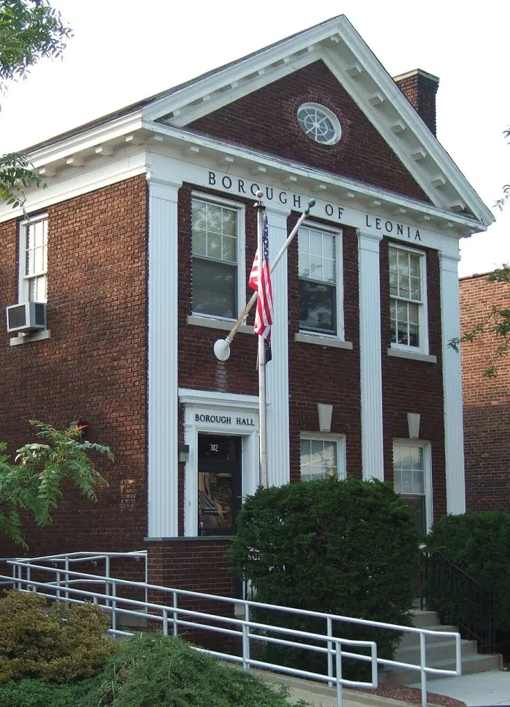 Borough Hall building in Leonia, NJ, featuring brick facade, American flag, and accessible ramp, symbolizing local governance and community services.