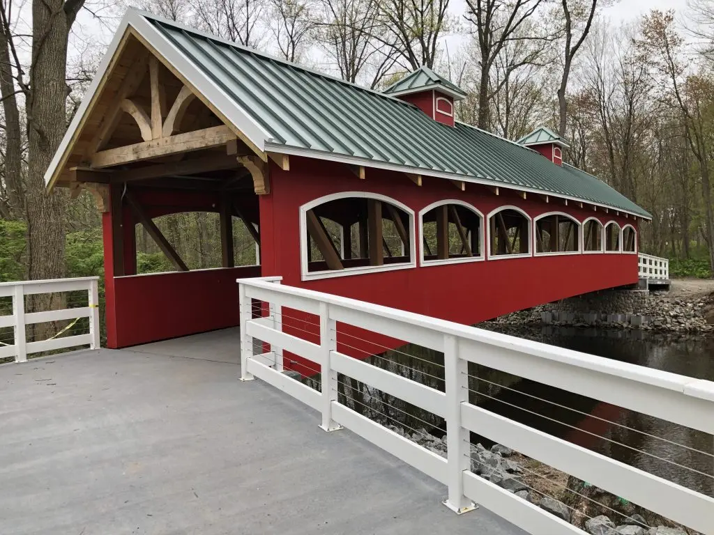 Red and white covered bridge over stream in Saddle River, NJ, protecting foundations from water