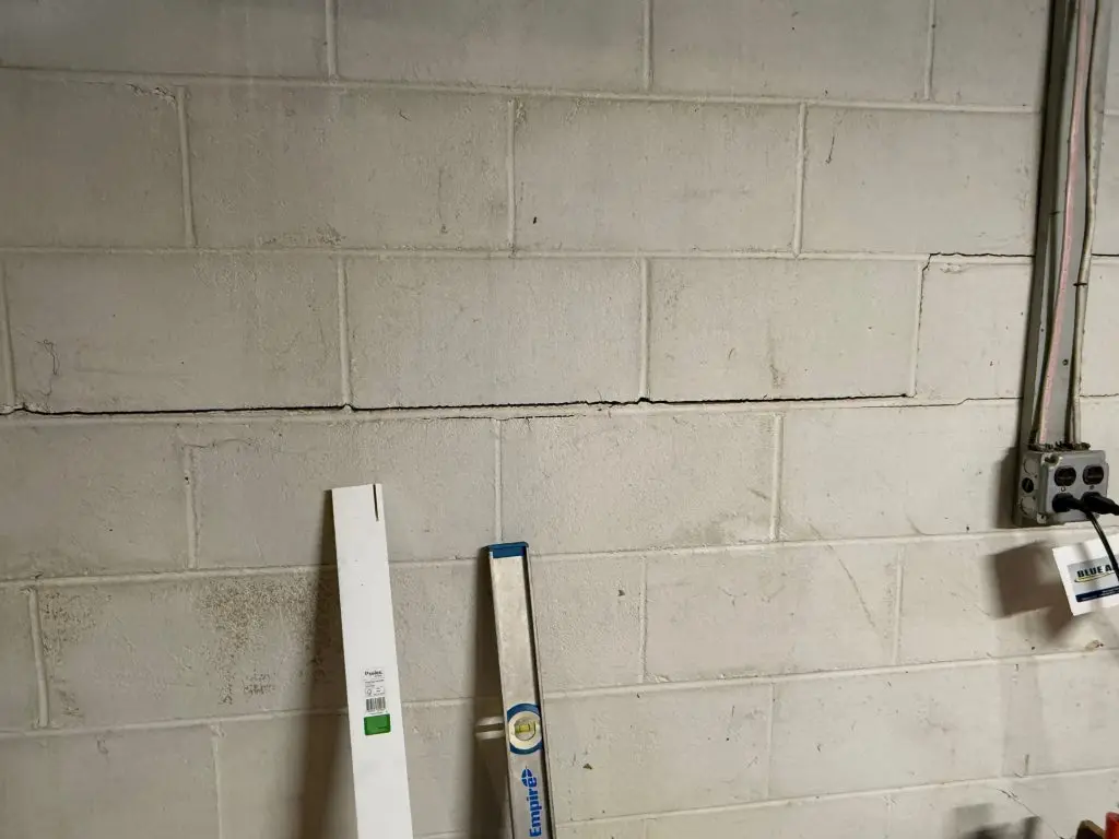Foundation crack repair in New Jersey basement wall with measuring tool.