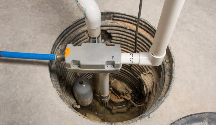 Installed sump pump system in a basement, featuring a pump, discharge pipe, and sump pit, essential for preventing water damage and maintaining a dry environment.