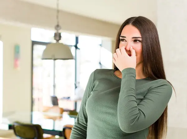 Woman smelling air detecting musty odor indicating crawl space mold or mildew.