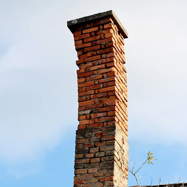 Leaning brick chimney showing foundation issues and need for repair.