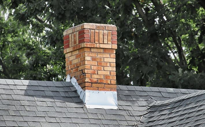 Leaning brick chimney indicating potential foundation issues and structural damage.