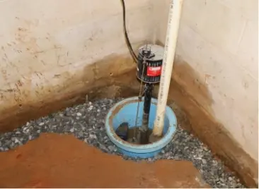Sump pump system installed in a basement with gravel drainage and water discharge.