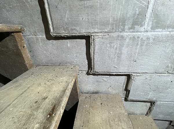 large crack in cinderblock by stairs
