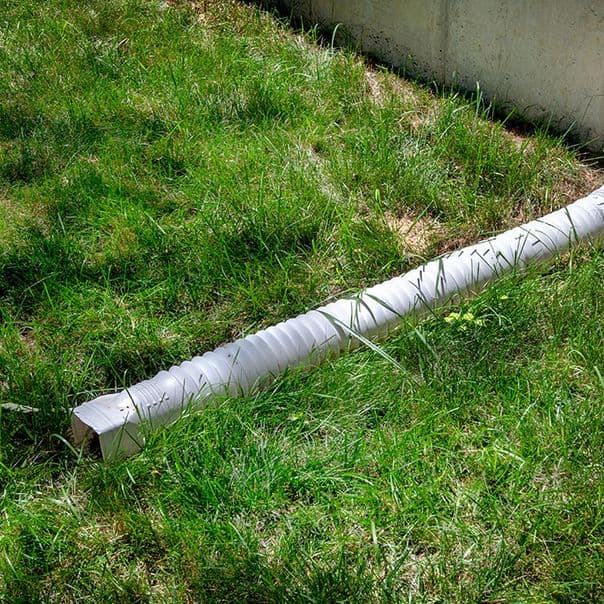Poorly graded lawn and drainage pipe near foundation, contributing to crawl space moisture.