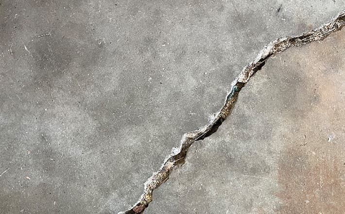 Large floor crack indicating potential foundation problems and structural damage.