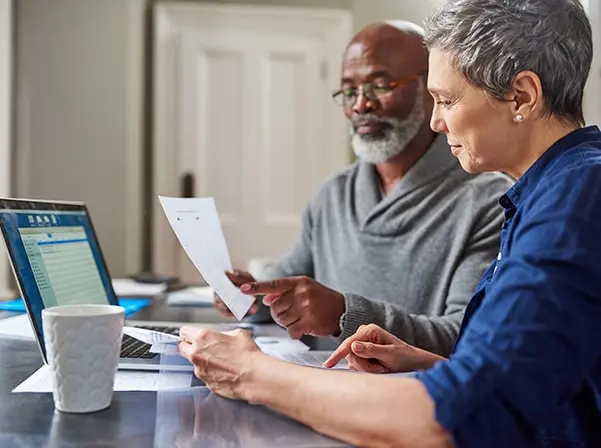 people looking at computer and paper