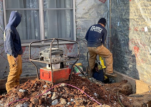 Foundation Solutions Group team repairing foundation with equipment and local construction expertise.