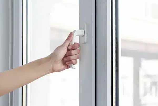 Hand gripping window handle demonstrating sticking door and window issues, foundation problems.