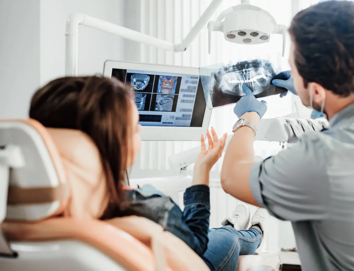 Dentist reviewing dental X-rays with a patient seated in the treatment chair