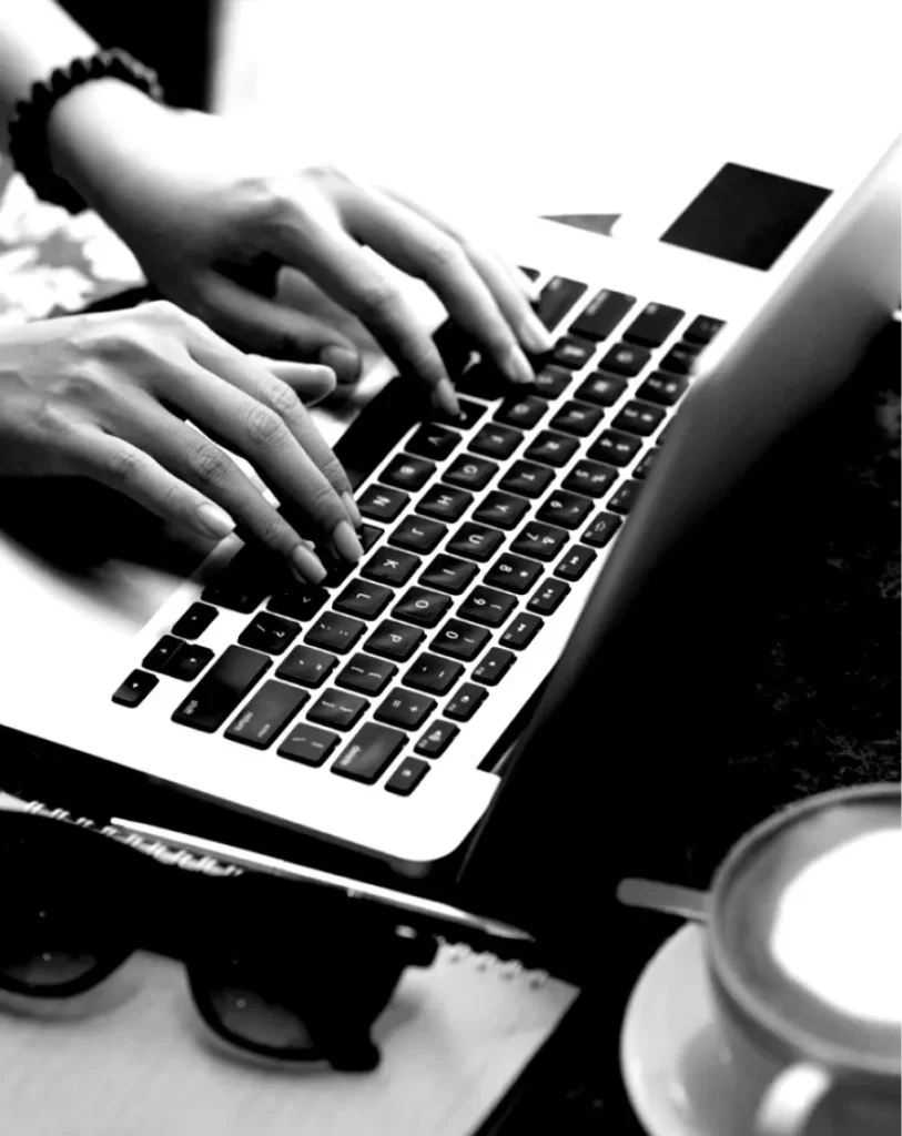 Hands typing on laptop with coffee nearby