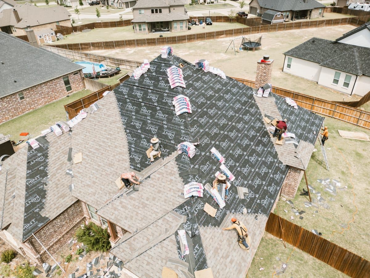 workers on top of shingles roof making repairs